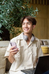 Non binary Asian student man sitting in modern coffee shop using laptop computer