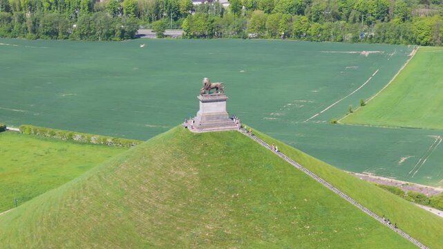 complete monument visitors heading down stairs green grass trees open fields lion's mound waterloo belgium right to left drone panning shot leeuw van captivating right-to-left 