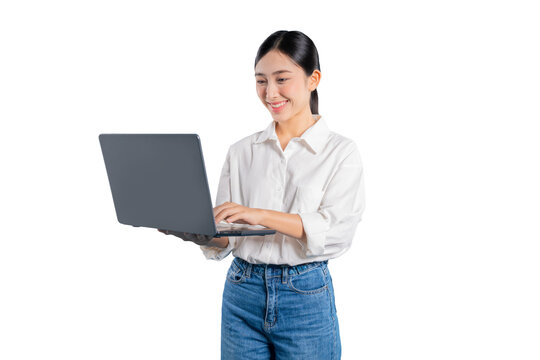 Asian woman smiles pleasantly as she holds a laptop and works, looking focused and content while typing or reading from the screen against a solid png background.
