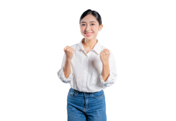 Asian woman in a white shirt and jeans clenches both fists in excitement, celebrating a success with a bright and energetic smile against a solid png background.
