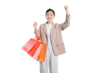 A triumphant young Asian woman joyfully raises one arm in a victory gesture while holding shopping bags, celebrating a successful shopping day against a solid png background.
