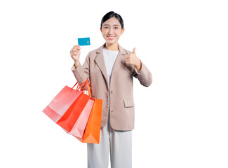 A happy young Asian woman gives a thumbs-up while holding shopping bags and a credit card, signifying approval and satisfaction with using the card for her purchases.
