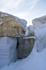 Large snow-covered rocks with intricate textures and patterns, surrounded by a winter landscape,...