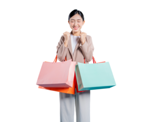 A cheerful young Asian woman in a blazer holds colorful shopping bags, clenching her fists in excitement and smiling brightly, celebrating a successful shopping day against a png background.

