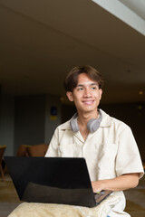 Non binary Asian student man sitting in modern coffee shop using laptop computer