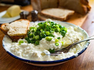 Cottage cheese with chives and bread on wooden table