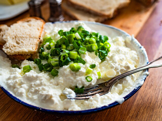 Cottage cheese with chives and bread on wooden table
