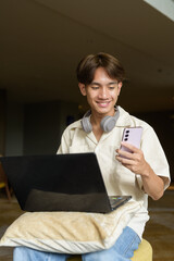 Non binary Asian student man sitting in modern coffee shop using laptop computer