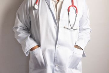 Doctor wearing white coat and red stethoscope with hands in pockets