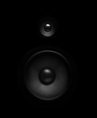 Black audio speaker with woofer and tweeter drivers isolated on a dark background, highlighting...