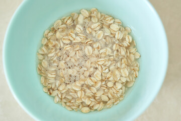 Close-up of soaking oatmeal in light blue bowl with bubbles and water.