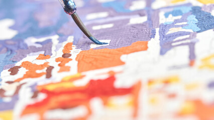 Close up of paintbrush applying vibrant colors on canvas for abstract art creation.