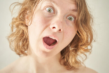 Caucasian female with curly hair showing surprised expression close-up portrait.