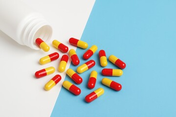 Red and yellow capsules on a blue backdrop with blank space for labeling, representing pharmaceutical treatment