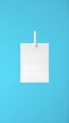 Blank white paper square hanging with wooden clip on bright blue background mockup