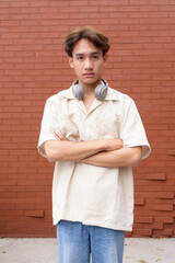 Non binary cute Asian young gay man against brick wall