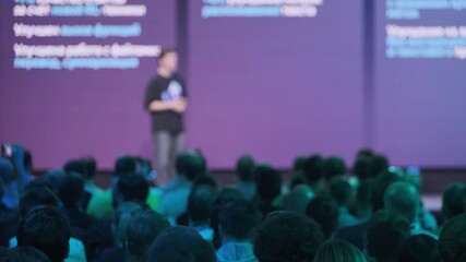Blurred image of a presenter on stage during a professional conference with an audience in a corporate setting focusing on technology and innovation - Powered by Adobe