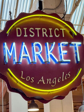 Los Angeles, California, USA - April 18, 2024: Bright neon sign reading "District Market Los Angeles" hanging inside the Grand Central Market, a popular indoor food market