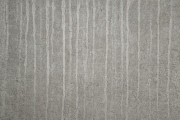 Fototapeta premium Vertical streaks and markings on a grey concrete wall surface