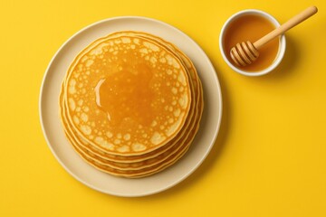 Golden stack of pancakes with honey on a yellow background, top view during Maslenitsa festival