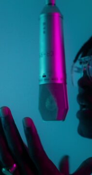 A man is rapping into a microphone. The camera moves from close-up of his face to the general plan