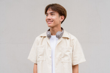 Non binary cute Asian young gay man thinking against studio background