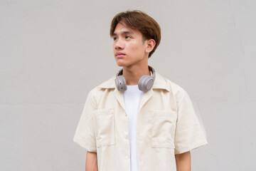 Non binary cute Asian young gay man thinking against studio background