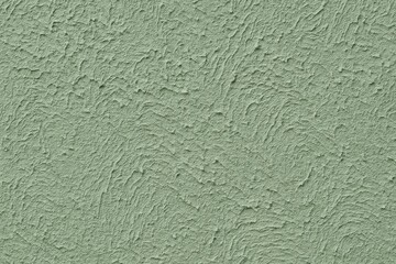 Textured greenish plaster with a coarse finish and an abstract backdrop.