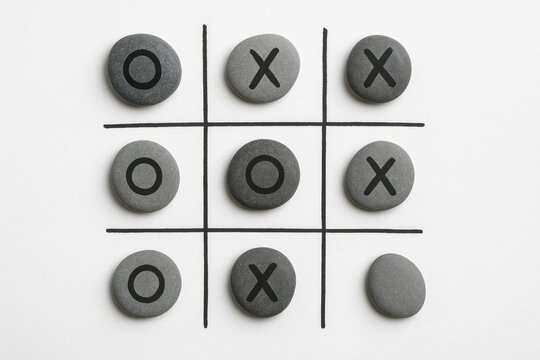 Bird's-eye perspective of a classic paper tic tac toe game featuring marked X and O symbols.