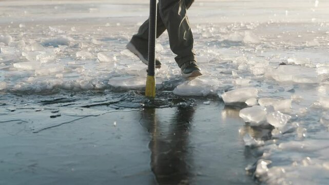 A man crushes ice as golden sunlight illuminates the crystalline frozen water