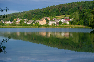 Obraz premium reflection of trees and small village in the water of lake 