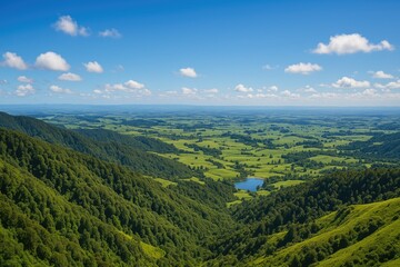Naklejka premium A breathtaking landscape viewed from a mountain summit, showcasing expansive rolling hills, vibrant greenery, and farmland under a clear blue sky