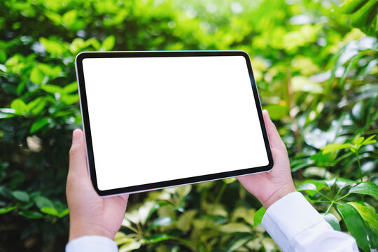Mockup image of a woman holding digital tablet with blank white desktop screen in the nature outdoors - Powered by Adobe
