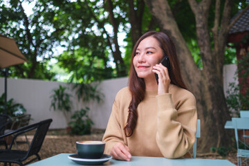 Portrait image of a young woman talking on mobile phone in the outdoors cafe