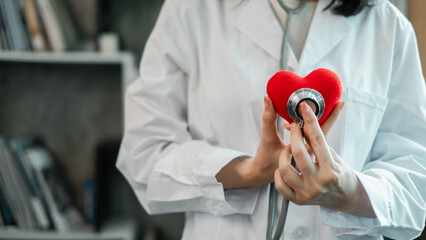 Close-up of a healthcare worker using a stethoscope on a heart-shaped object, symbolizing care and...