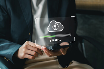 A business professional holds a smartphone displaying a digital backup cloud icon, symbolizing data...