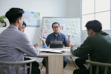 Male Teacher Wearing Glasses Passionately Speaks To Students Around Table
