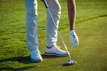 Golfer placing ball on green grass during a sunny day