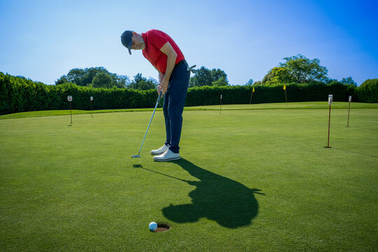 Golfer putting ball on green during sunny day practice