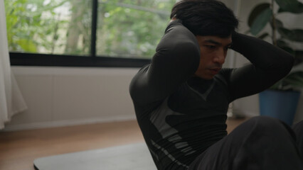 Asian male exercising abs indoors.