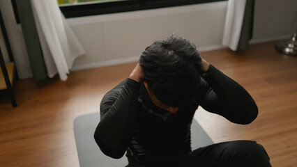 Asian male exercising abs indoors.