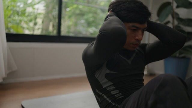 Asian male exercising abs indoors. - Powered by Adobe