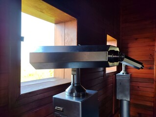 Horizontal photo image of public coin operated telescope binocular viewer on sea shore close up on...