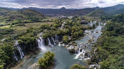 Fototapeta premium Bird's-eye view of the park's waterfalls, green hills, and idyllic scenery; The wide river flows through lush forests, raindrops falling from high waterfalls, splashes, natural beauty and tranquility.