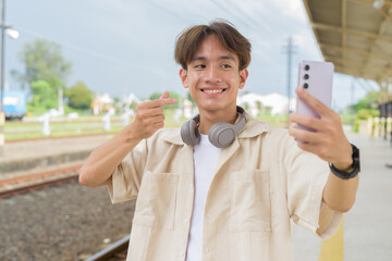 Young non binary tourist traveler in train station using phone