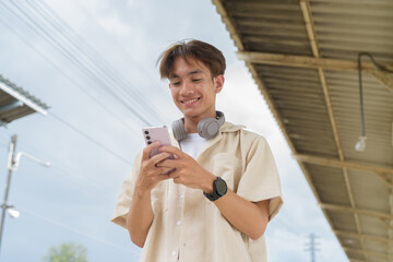 Young non binary tourist traveler in train station using phone