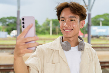 Young non binary tourist traveler in train station using phone