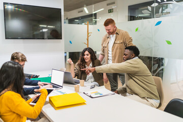 Diverse team of marketing professionals working together on a project, analyzing data and strategizing in a modern coworking office