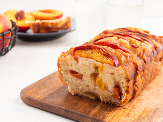 Peach cake loaf on wooden cutting board on white backgroud