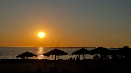 Sunset at Homem do Leme beach in Porto, Portugal, on July 8, 2025, showing silhouetted beach umbrellas and cranes against a golden sky, capturing a peaceful holiday evening by the Atlantic Ocean.